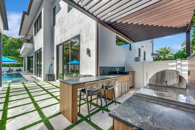 view of patio with sink, area for grilling, and a fenced in pool