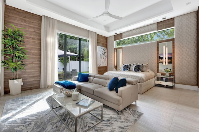 bedroom with wood walls, a tray ceiling, access to outside, and ceiling fan