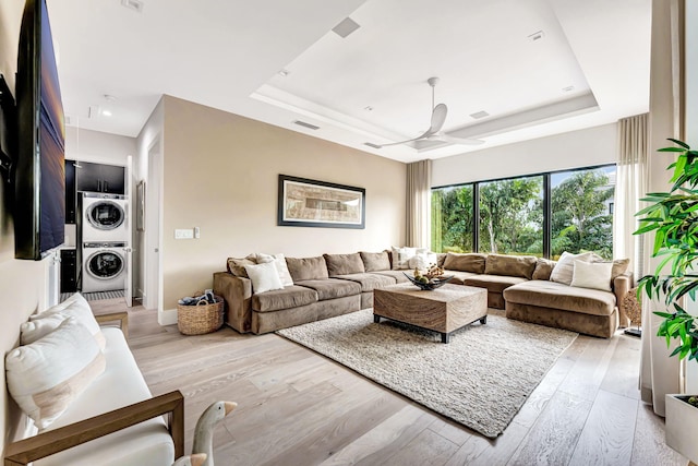 200 NE 6th St, Boca Raton, FL 33432 - living room with a tray ceiling, stacked washer / dryer, visible vents, and light wood-style flooring