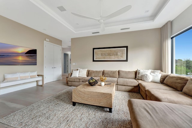 living room featuring ceiling fan, wood-type flooring, and a raised ceiling