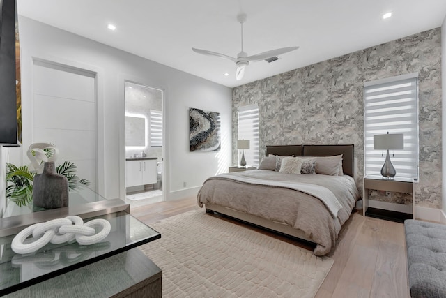 bedroom featuring ensuite bath, light hardwood / wood-style floors, and ceiling fan