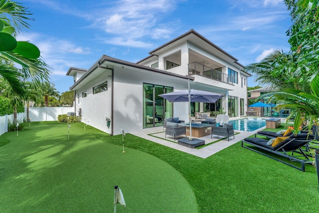 rear view of property featuring a balcony, an outdoor living space, a patio, a fenced in pool, and ceiling fan