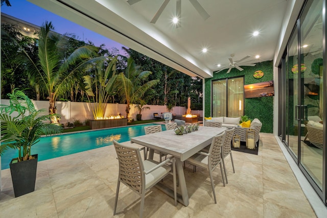 pool at dusk featuring ceiling fan, a patio area, and outdoor lounge area