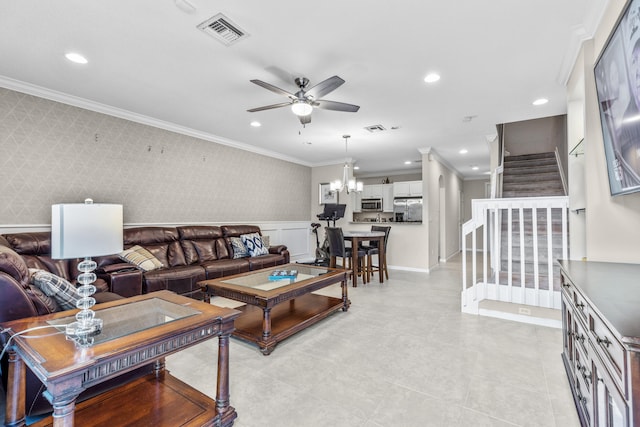 living room with ceiling fan with notable chandelier and crown molding