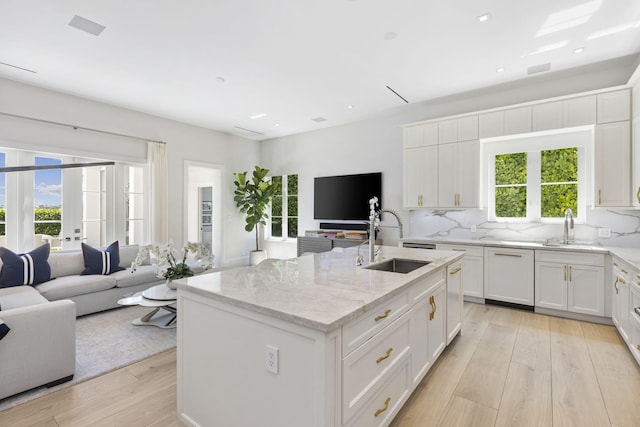 kitchen featuring sink, light hardwood / wood-style flooring, white cabinets, and a center island with sink