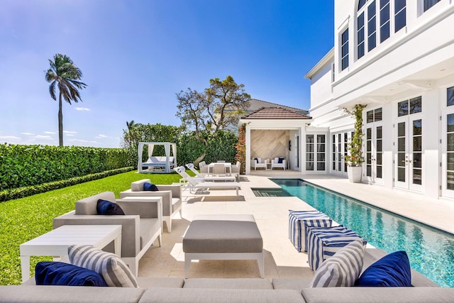 view of swimming pool with french doors, an outdoor living space with a fireplace, and a patio