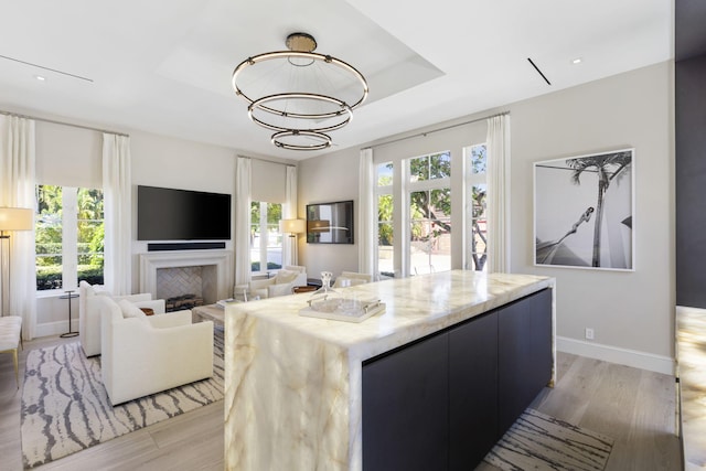 kitchen featuring a chandelier, a center island, a raised ceiling, and light hardwood / wood-style flooring