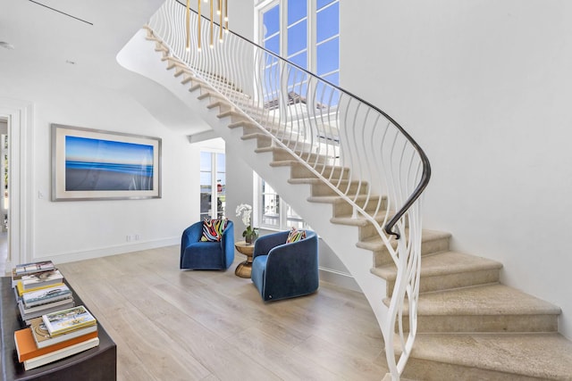 stairway with baseboards, a high ceiling, and wood finished floors