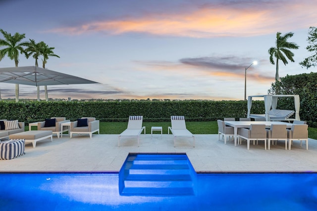 pool at dusk featuring a patio area