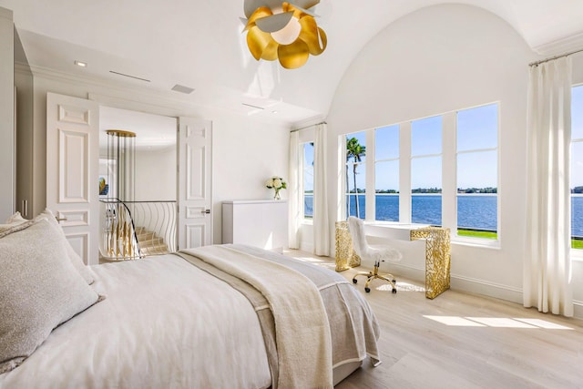 bedroom featuring lofted ceiling, a water view, wood finished floors, visible vents, and baseboards