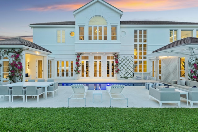 rear view of house with french doors, stucco siding, outdoor lounge area, a patio area, and an outdoor pool