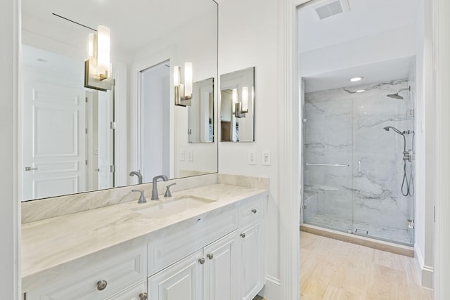 bathroom featuring visible vents, vanity, a marble finish shower, and wood finished floors