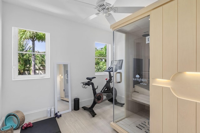 workout room featuring light wood-type flooring, ceiling fan, and baseboards