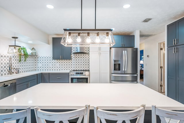 kitchen featuring sink, stainless steel appliances, decorative light fixtures, and a kitchen bar