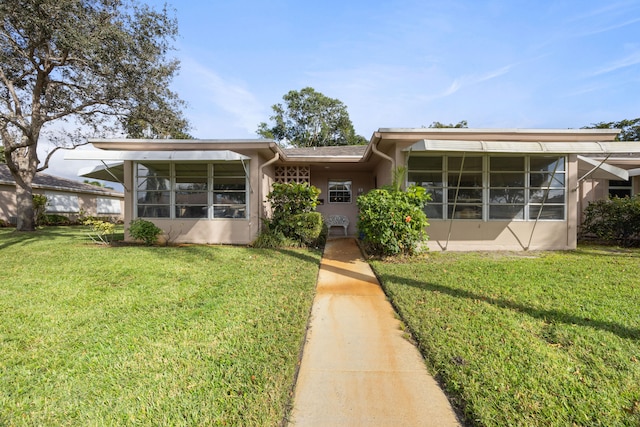 view of front of home featuring a front lawn and a sunroom