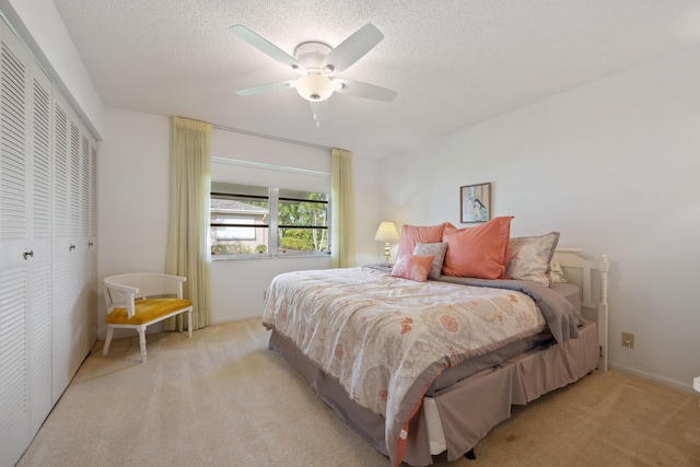 carpeted bedroom with ceiling fan, a textured ceiling, and a closet