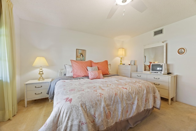 carpeted bedroom featuring ceiling fan and a textured ceiling