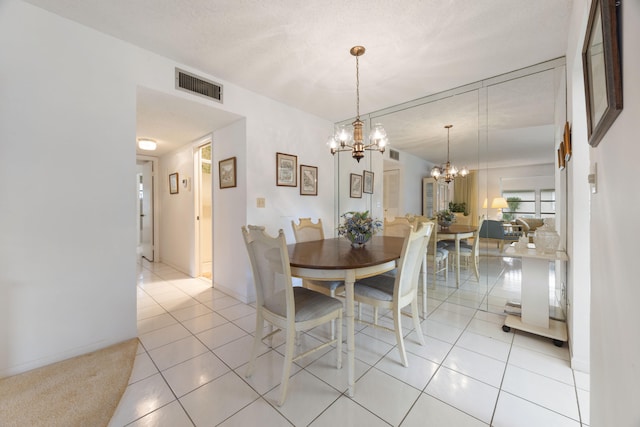 dining area featuring an inviting chandelier, a textured ceiling, and light tile patterned floors