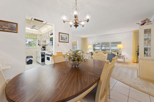 tiled dining area featuring a wealth of natural light and ceiling fan with notable chandelier