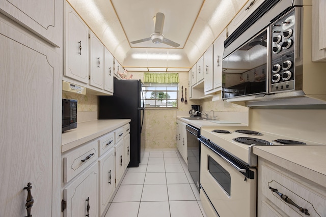 kitchen featuring black appliances, a raised ceiling, light tile patterned floors, and white cabinets