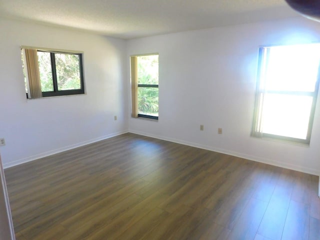 unfurnished room with a wealth of natural light and dark wood-type flooring