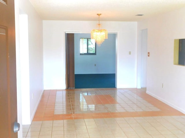 tiled empty room with an inviting chandelier