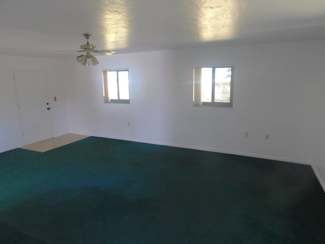 carpeted spare room featuring a wealth of natural light and ceiling fan