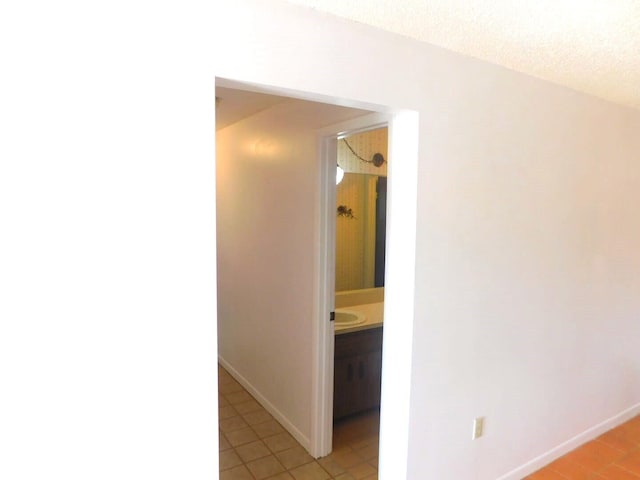 hallway featuring light tile patterned floors and a textured ceiling