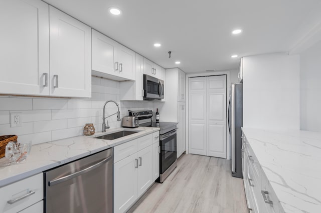 kitchen featuring white cabinets, stainless steel appliances, sink, and light wood-type flooring