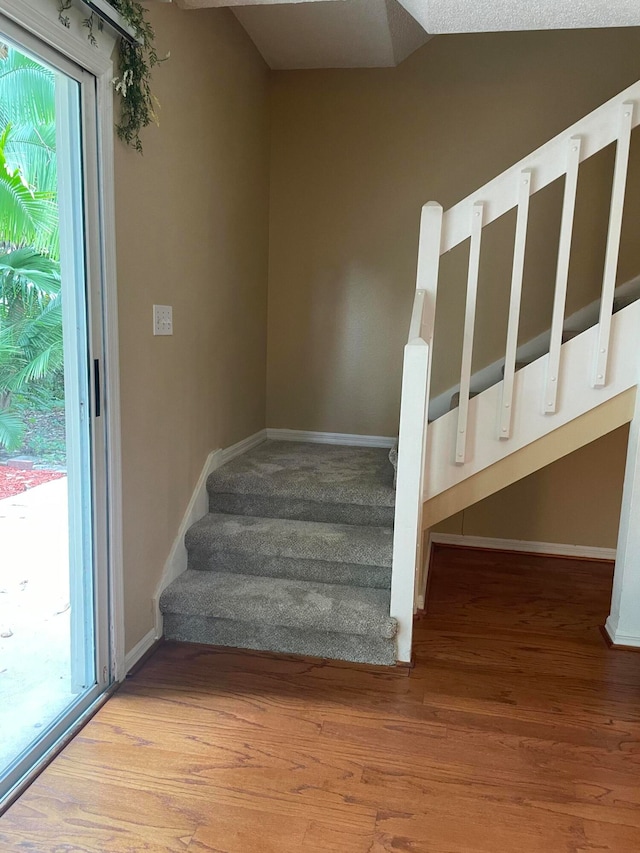 stairway featuring wood-type flooring and vaulted ceiling