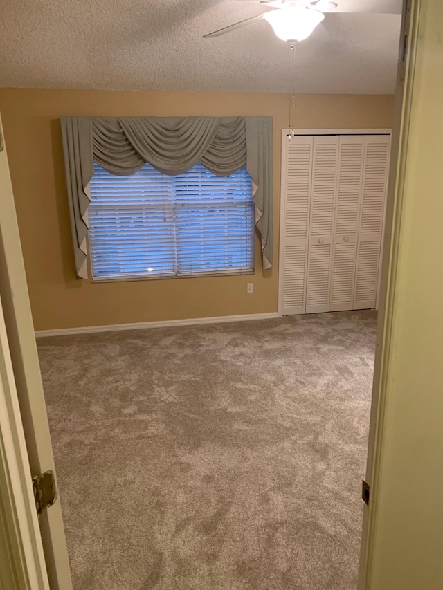 unfurnished bedroom with a closet, a textured ceiling, carpet, and ceiling fan