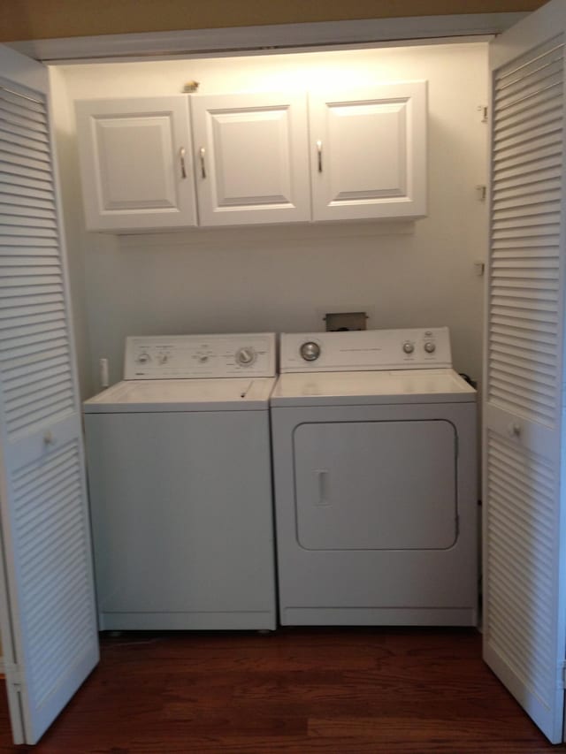 laundry room featuring washer and clothes dryer, dark hardwood / wood-style floors, and cabinets