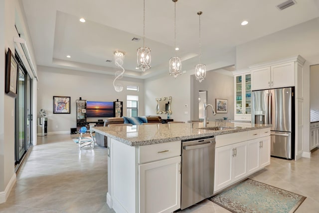 kitchen featuring white cabinetry, sink, an island with sink, decorative light fixtures, and appliances with stainless steel finishes