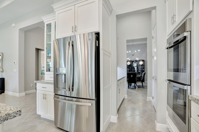 kitchen featuring white cabinets, stainless steel appliances, light stone counters, and light tile patterned flooring