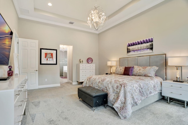 bedroom featuring an inviting chandelier, light colored carpet, a raised ceiling, and connected bathroom