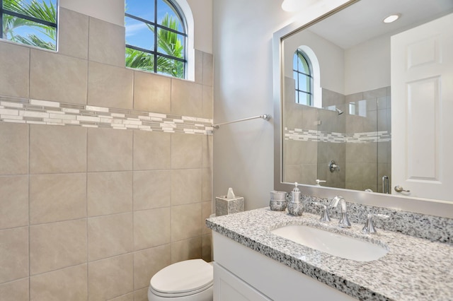 bathroom featuring plenty of natural light, toilet, a tile shower, and vanity