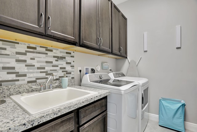 clothes washing area featuring separate washer and dryer, sink, light tile patterned floors, and cabinets