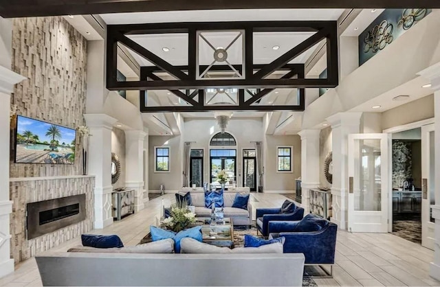 living room with decorative columns, light hardwood / wood-style floors, and a high ceiling