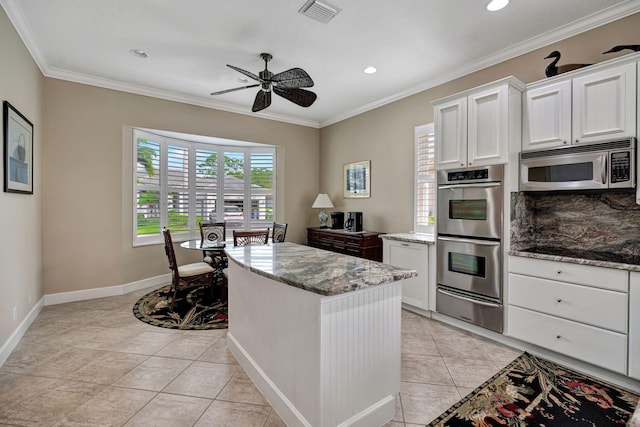 kitchen featuring light stone counters, stainless steel appliances, and white cabinets