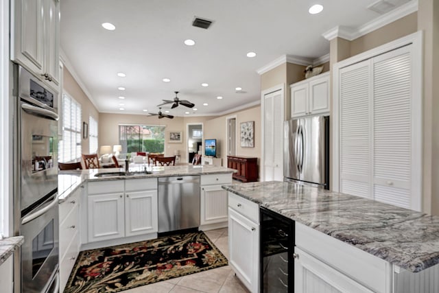 kitchen featuring sink, appliances with stainless steel finishes, white cabinets, light tile patterned flooring, and beverage cooler