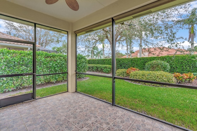 unfurnished sunroom featuring ceiling fan and a wealth of natural light