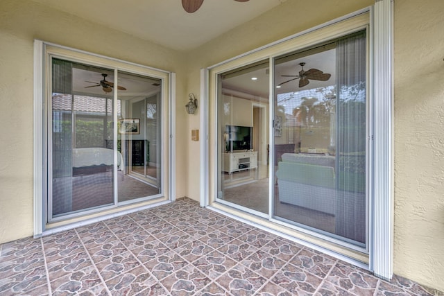 view of exterior entry with ceiling fan and a patio