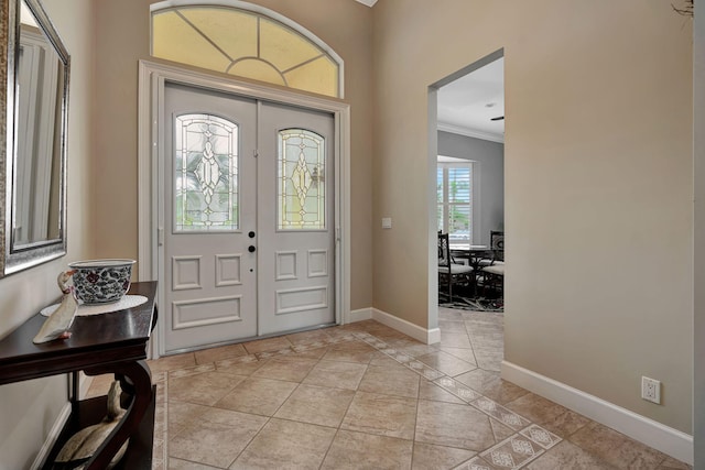 foyer entrance with crown molding, light tile patterned flooring, and french doors