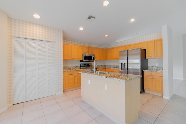 kitchen featuring light tile patterned floors, a kitchen island with sink, light stone countertops, sink, and stainless steel appliances