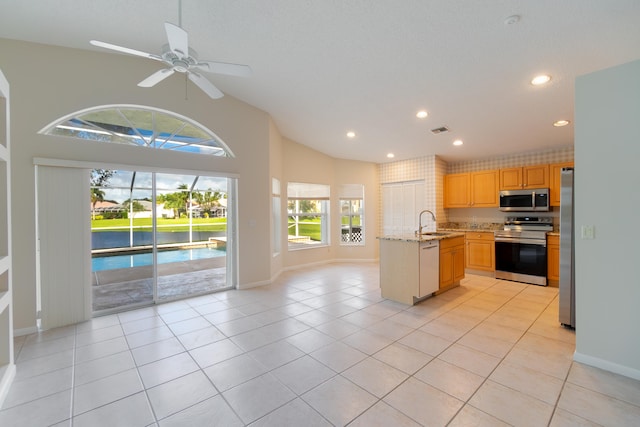 kitchen featuring light brown cabinets, sink, light tile patterned floors, appliances with stainless steel finishes, and light stone counters