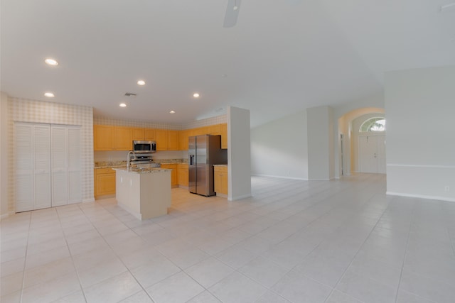 kitchen featuring a center island, stainless steel appliances, light stone counters, and light tile patterned floors