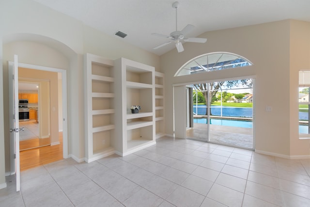 tiled spare room featuring ceiling fan, a textured ceiling, vaulted ceiling, and built in shelves