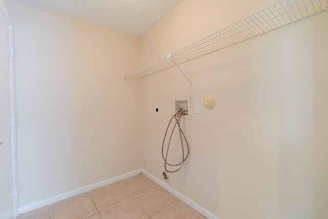 clothes washing area with hookup for a washing machine, hookup for an electric dryer, a textured ceiling, hookup for a gas dryer, and light tile patterned floors