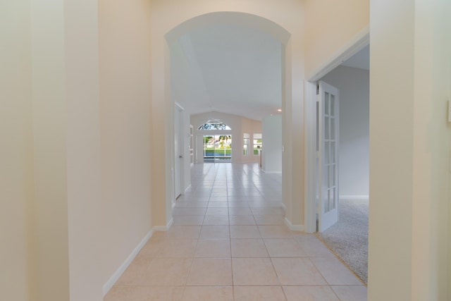 corridor featuring vaulted ceiling and light tile patterned floors