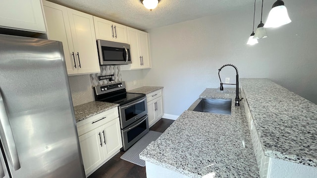 kitchen featuring appliances with stainless steel finishes, sink, hanging light fixtures, white cabinets, and light stone counters